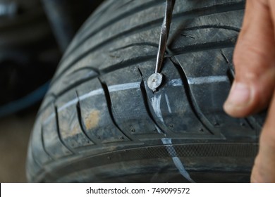 Solve Problem Wheel In Garage Auto Repair Shop Service. Replacement Repairman Fixing Car's Tire Trying To Remove Nail From Hole. Flat Tire. Accident With Punctured Tires Concept.