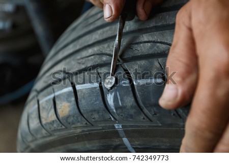 solve problem wheel in garage auto repair shop service. replacement repairman fixing car's tire trying to remove nail from hole. Flat tire. Accident with punctured tires concept.
