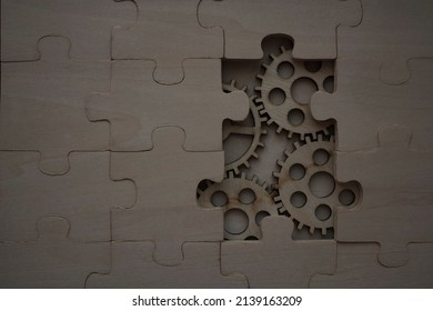 Solving The Problem Concept - Puzzles And Cogwheels. Wooden Gears Under The Puzzle, The Concept Of Moving To The Next Level. Cog Wheels Coming Out From Underneath A Jigsaw Puzzle