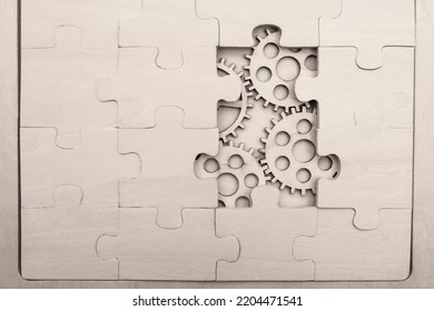 Solving The Problem Concept - Puzzles And Cogwheels. Wooden Gears Under The Puzzle, The Concept Of Moving To The Next Level. Cog Wheels Coming Out From Underneath A Jigsaw Puzzle.