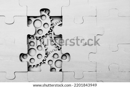solving the problem concept - puzzles and cogwheels. wooden gears under the puzzle, the concept of moving to the next level. Cog wheels coming out from underneath a jigsaw puzzle.