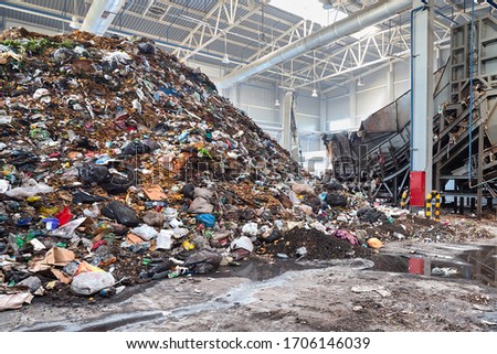 Solving problem of environmental pollution with waste at garbage processing plant - huge pile of garbage prepared for loading to conveyor belt for further sorting and processing with copyspase.