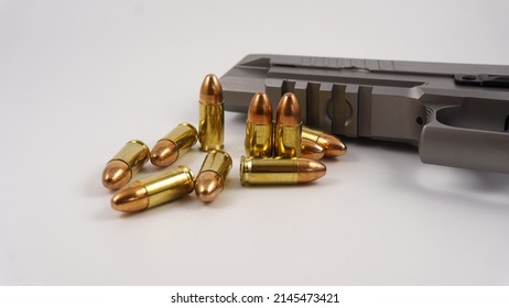 Some 9mm rounds lay and stay before an 9mm Pistol in Gunmetal