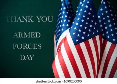 some american flags and the text thank you and armed forces day against a dark green background