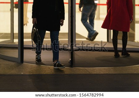 Some bisnesspersons leaving the office building, some coming. Revolving door and men' and women' feet photography. Urban office lifestyles in the end of day. 