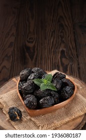 Some Black Dates On A Wooden Heart Shaped Bowl