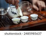 Some ceremony sets are on table. The tea table is on the table. Tea sets such as teapots and cups are in wooden trays. process of pouring tea during a tea ceremony in China.