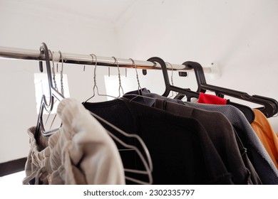 Some clothes are hung using on iron hangers