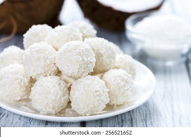 Some Coconut Pralines (close-up shot) on wooden background