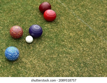 Some colored lawn bowls clustered around the white ball known as the jack