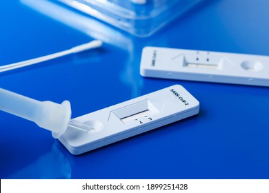 some covid-19 rapid antigen test kits, with the diagnostic test devices and some nasopharyngeal swabs, on a blue surface
