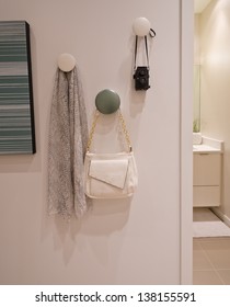 Some decorations hanging on the wall hooks. Scarf, kerchief, bag, pouch and photo camera. Interior design. Fragment.