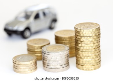 some different euro coin stacks with car in background