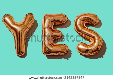 some golden letter-shaped balloons forming the word yes on a blue background