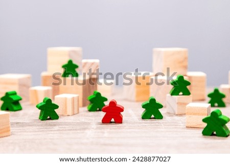 Some green game pieces and one red standing on wooden blocks, depicting teamwork and leadership concepts.