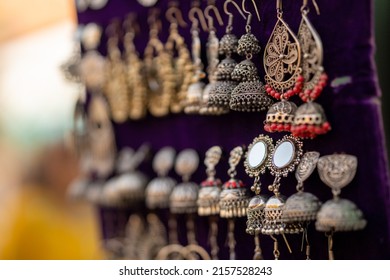 Some Indian-styled silver earrings handing on a velour board 