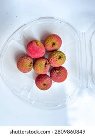 Some lechees in a clear plastic container isolated in a white background