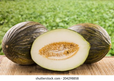 Some melons over a wooden surface on a plantation of melons as background