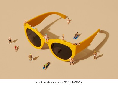 some miniature people, wearing swimsuit, relaxing on top of a pair of yellow plastic-rimmed sunglasses and some more miniature people standing around, against a pale brown background