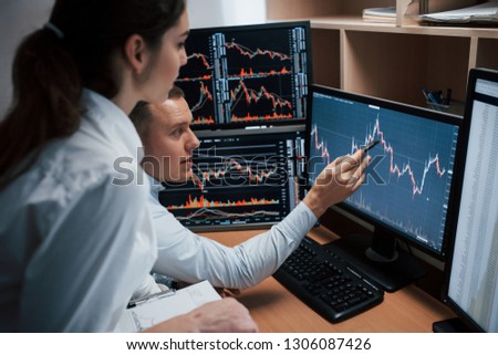 Some nice results. Team of stockbrokers are having a conversation in a office with multiple display screens.