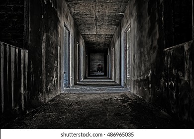 some people sitting in the room at end of scary hallway walkway in abandoned building