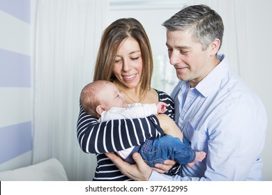 some Proud Parents Holding Baby in the bedroom