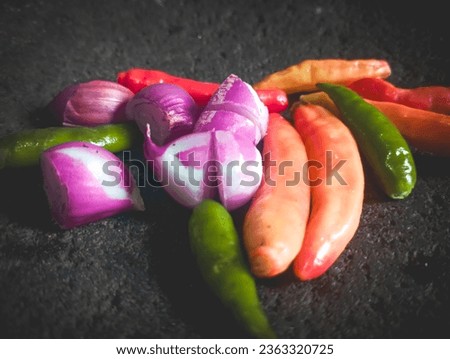 some red chili peppers, green chili peppers, shallots, on a stone. are the basic spices of Indonesian cuisine. In some photo angles (Closeup, low view, soft focus) 