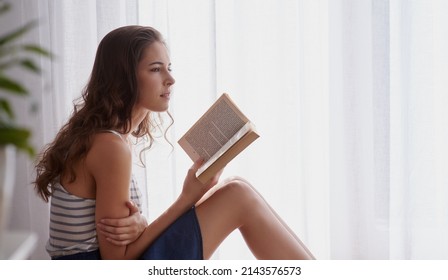 Some Stories Leave A Lasting Impression.... Cropped Shot Of A Young Woman Reading A Book At Home.