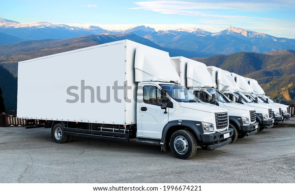 Some trucks are parked in a parking lot next to\
a logistics warehouse by the river. Several trucks are lined up in\
the parking lot. Logistic\
transport