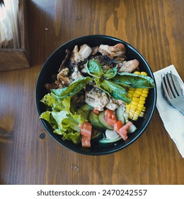  some vegetables, namely sliced ​​tomatoes, corn, chicken with basil sauce in black bowl
