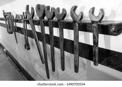 Some very old engineer tools hung up on a brick wall, in an underground location.