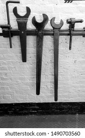 Some very old engineer tools hung up on a brick wall, in an underground location.