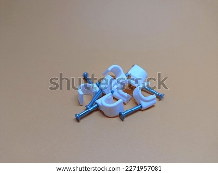 some white cable clamps made of plastic wrapped with nails