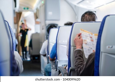 Somebody Is Reading The Menu On The Seat In The Plane, And Ready To Order To Air Hostess.