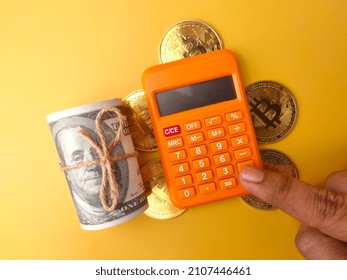 Someone Is Calculating Using A Calculator With Golden Bitcoin And Banknotes On A Yellow Background.