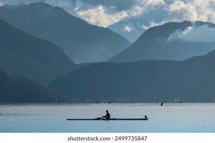 Someone canoeing on Lake Annecy with the mountains behind them - Powered by Shutterstock