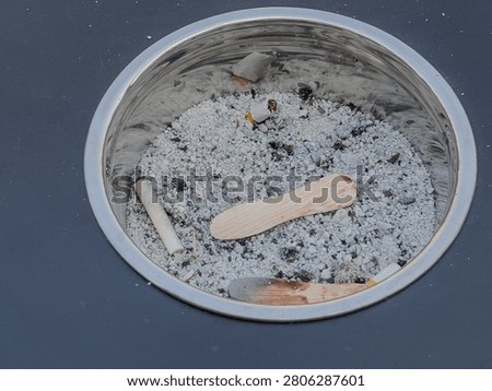 Someone carelessly throws an ice cream stick in a cigarette ashtray