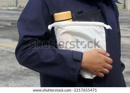 Someone Carrying a Pouch of Lunchbox using her Righthand