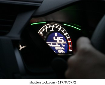 Someone driving the car and control his car by steering wheel looking at speed o meter to see the speed.