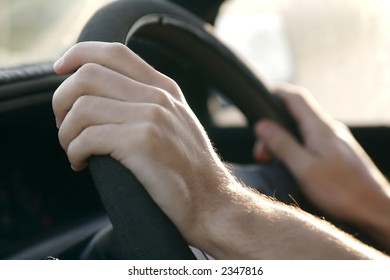 Someone Driving A Car And Holding The Steering Wheel