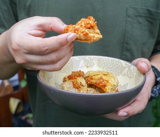 Someone is eat fried tofu with chili. Tahu walik pedas. Indonesian traditional food.  - Shutterstock ID 2233932511