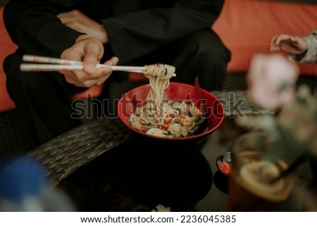 someone eating a bowl of spicy ramen noodles