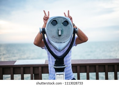 Someone Flashing Peace Signs Behind A Pier Binoculars