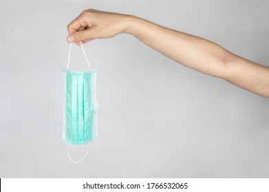 Someone Hand Holding A Surgical Mask. A Surgical Mask Is A Fitting Disposable Mask That Protects The Wearer's Nose And Mouth From Contact With Droplets.