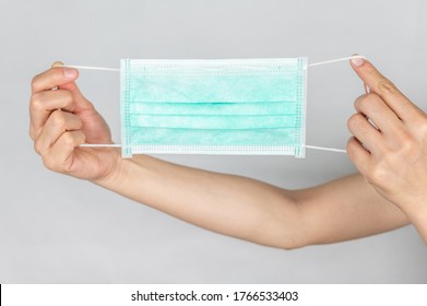 Someone Hand Holding A Surgical Mask. A Surgical Mask Is A Fitting Disposable Mask That Protects The Wearer's Nose And Mouth From Contact With Droplets.