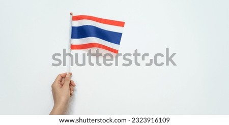 Someone hand holding a Thai flag against white background.