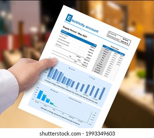 Someone Hand Holds Electricity Account Showing Their Home Energy Use.