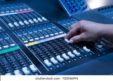 Someone hand working on Volume slide audio mixer in the control room of television broadcast. Mixdown 