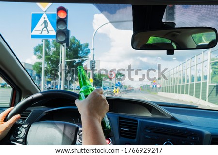 Someone hands driving and holding a bottle with alchohol. Drunk driving concept