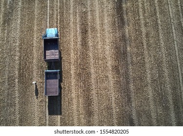 someone have a lot of work at the field. Truck in the field. Aerial shot of an agricultural wheat field, a combine harvester and a truck in Europe. Aerial View Of Rural Landscape. Harvesting Of Wheat